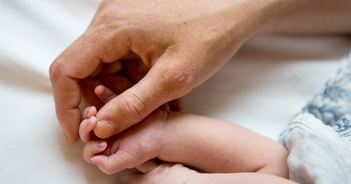 Parent's hand holding infant's hand